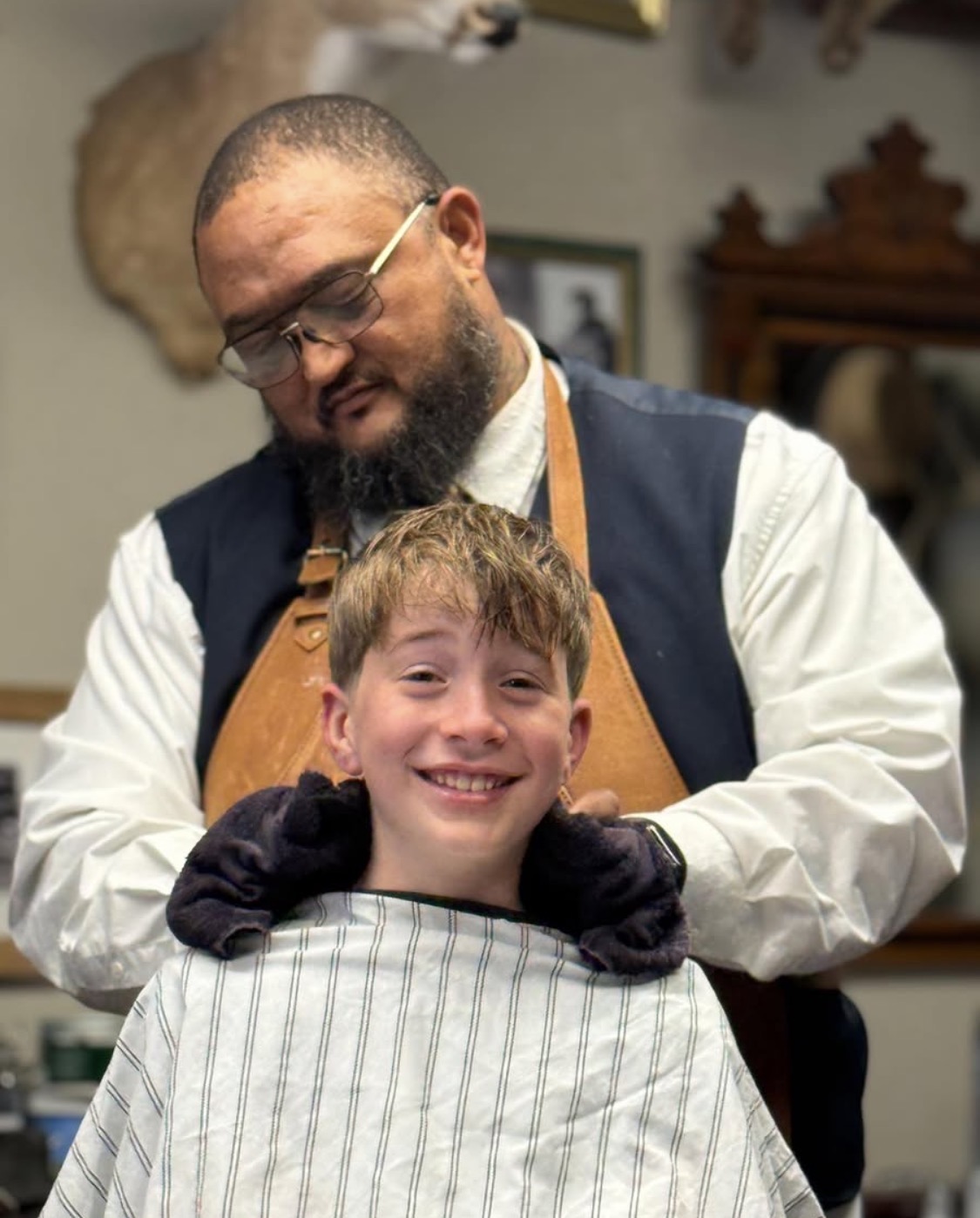 Barber with a smiling young client after a sensory-friendly haircut