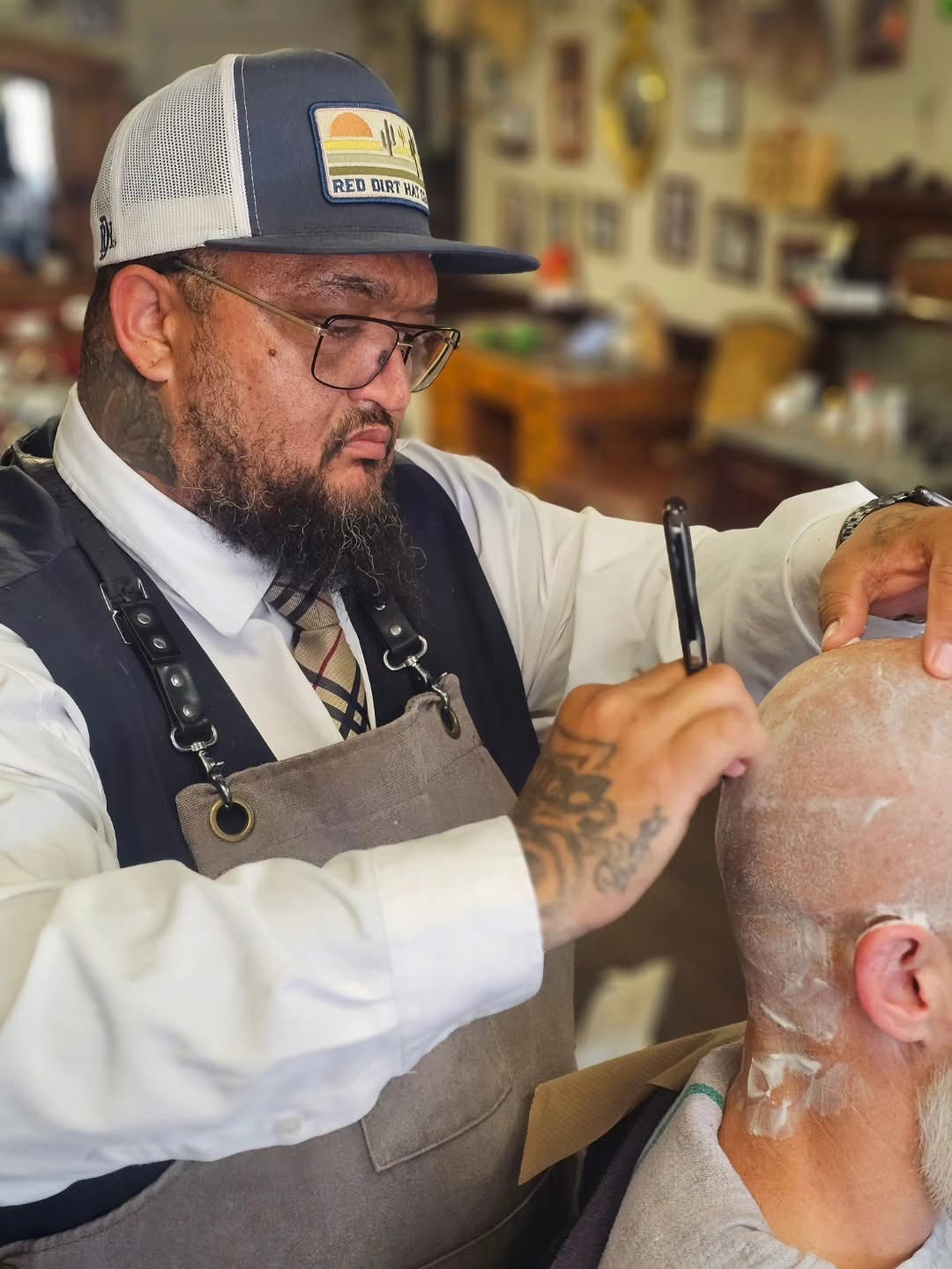 Barber shaving a client's head at Cedar Park Barber-Allen